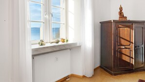 Et værelse med vindue, radiator, et træskab og en Buddha-figur.