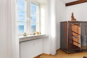 Una habitación con ventana, radiador, armario de madera y una estatua de Buda.