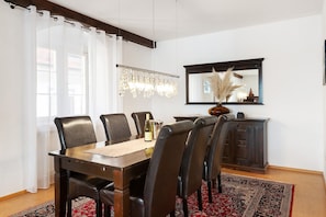 A dining area with a wooden table, six chairs, a chandelier, a mirror, and a cabinet. - Apartment 'Directly On The Überlingen' with Lake View and Wi-Fi (Überlingen)