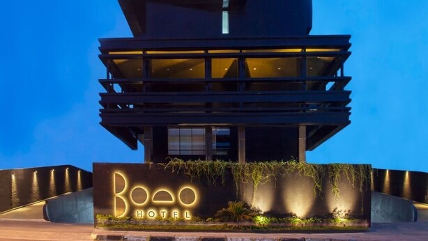 Un hotel moderno con un diseño arquitectónico único, con varios balcones y una entrada destacada con un cartel.