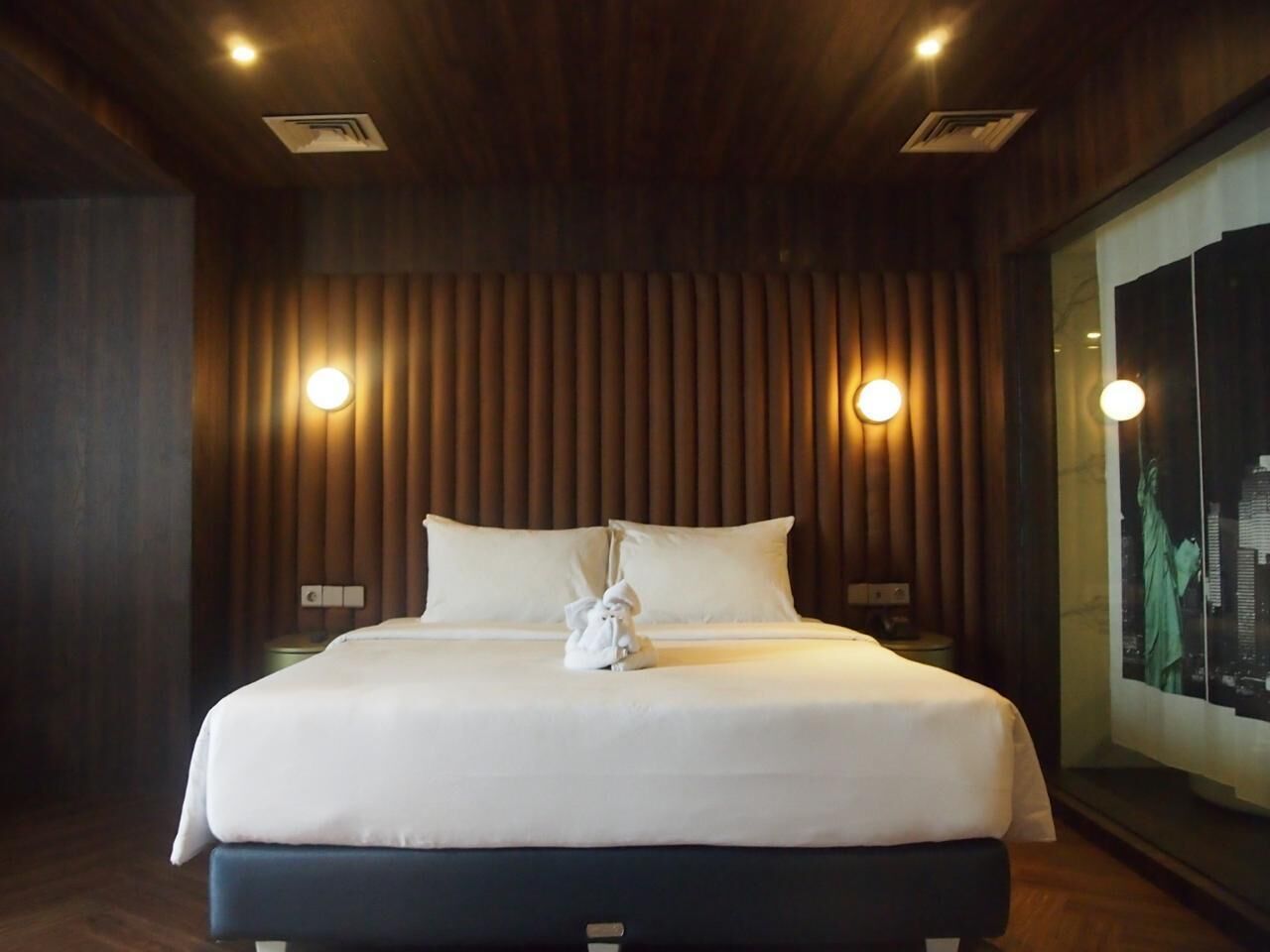 Ein Hotelzimmer mit einem großen Bett, Holzpaneelen und zwei Wandleuchten.