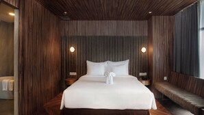 Una habitación de hotel moderna con una cama grande, paneles de madera y un banco junto a la ventana.
