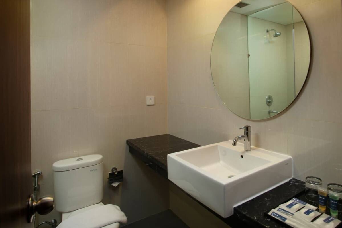 A bathroom with a toilet, a sink, a mirror, and a shower.