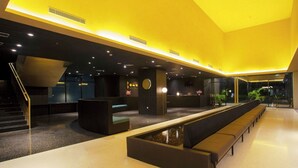 Un moderno vestíbulo de hotel con recepción, zona de estar y una escalera.