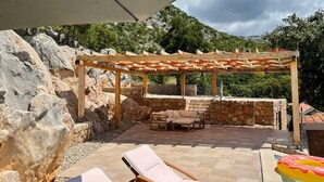 A covered outdoor seating area with stone walls and a pergola, overlooking a mountainous landscape. - Wonderful home with swimming pool and sauna. Sea view (Starigrad)