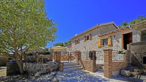 A stone house with a wooden door and steps leading to a porch. - Wonderful home with swimming pool and sauna. Sea view (Starigrad)