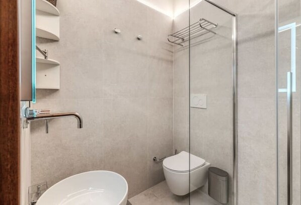 Un baño moderno con cabina de ducha de vidrio, inodoro blanco y bañera independiente.