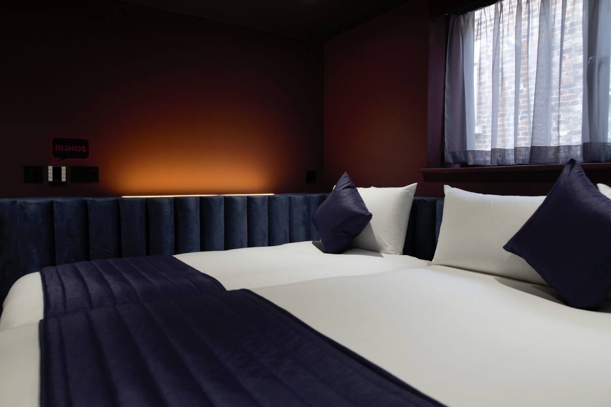 A neatly made bed with dark blue bedding, a headboard, and two pillows.