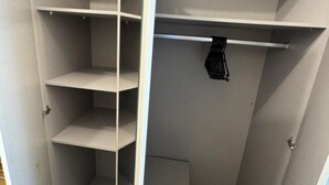 Ein begehbarer Kleiderschrank mit mehreren Regalen und einer Kleiderstange.