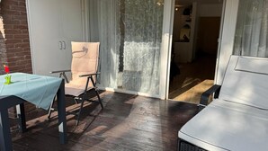 Eine Terrasse mit Tisch, Stühlen und einer Glastür, die zu einem Innenbereich führt.
