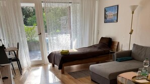 Ein Zimmer mit einem Bett, einem Sofa, einem Esstisch und einer Lampe.