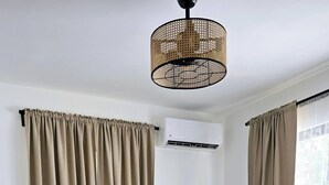 A modern bedroom with a grey and white patterned bedspread, a grey headboard, and a rattan ceiling light. - 2BR 2BA Backup Power AC Wifi Gym 24h Security Ideal for Long Stays (Santiago de los Caballeros)