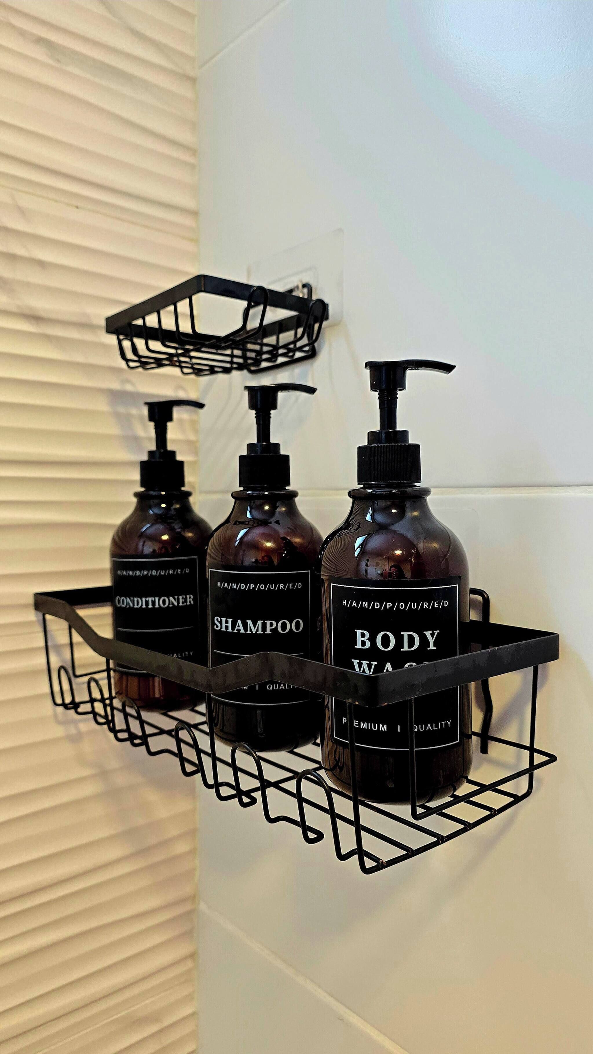 Estante metálico negro con tres botellas de productos de cuidado personal: acondicionador, champú y gel de baño.