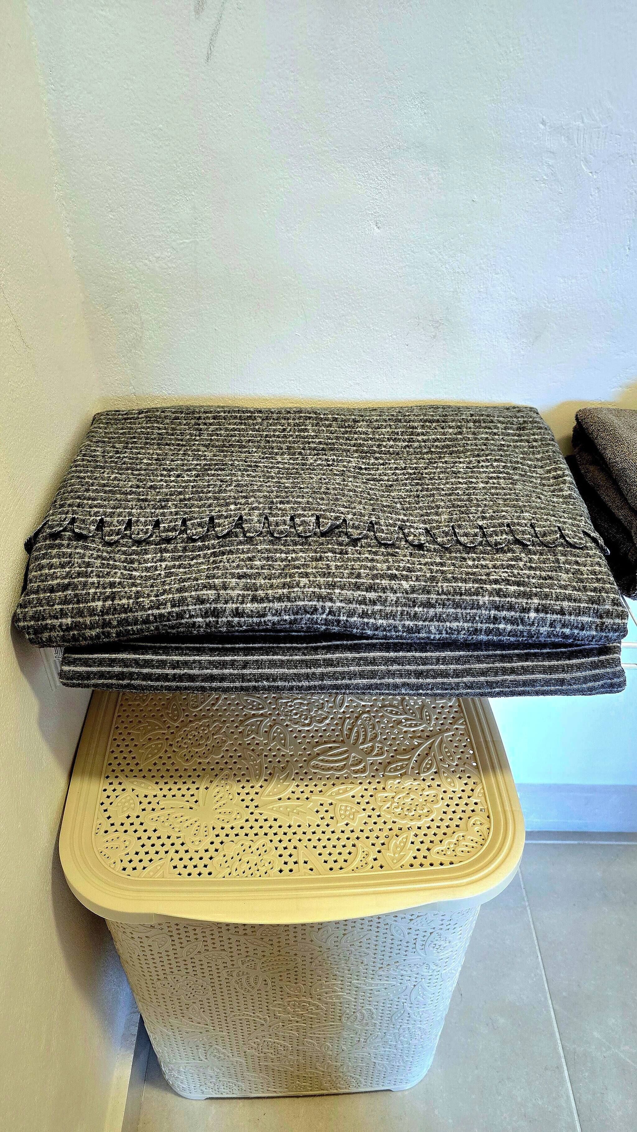 A stack of folded blankets on a woven basket.