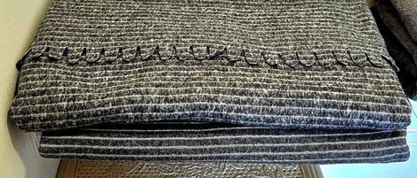 A stack of folded blankets on a woven basket.