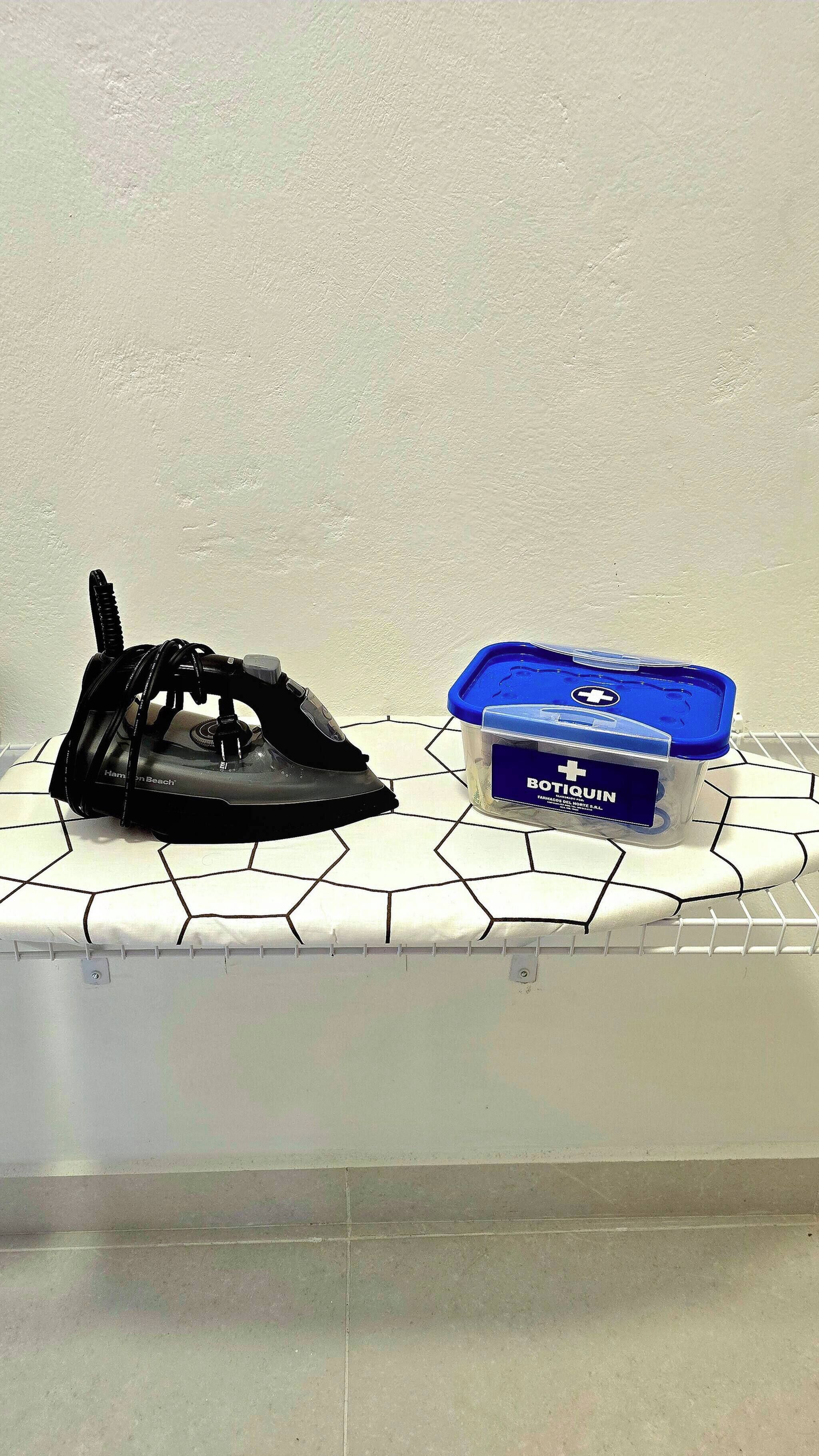 An iron and a container of Botiquin on a tiled surface.