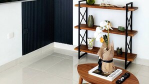 A modern living room with a TV mounted on the wall, a wooden coffee table, a round mirror, and a bookshelf with decorative items. - 2BR 2BA Backup Power AC Wifi Gym 24h Security Ideal for Long Stays (Santiago de los Caballeros)