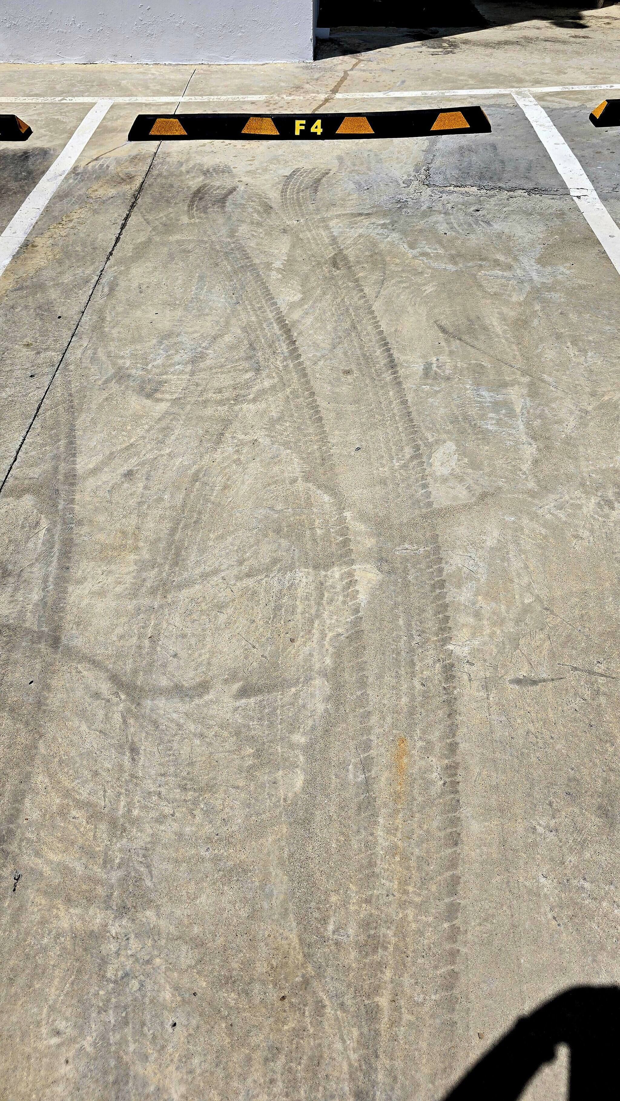 A parking area with concrete surface, marked lines, and a barrier with 'F4' and warning triangles.