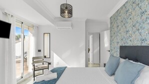 Een slaapkamer met een bed, een stoel, een spiegel en uitzicht.