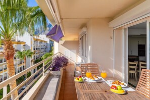 Un balcon avec une table préparée pour le petit-déjeuner, comprenant des fruits, des viennoiseries et une boisson.