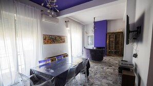 Un comedor con una mesa larga, sillas transparentes y una pared de acento morada.