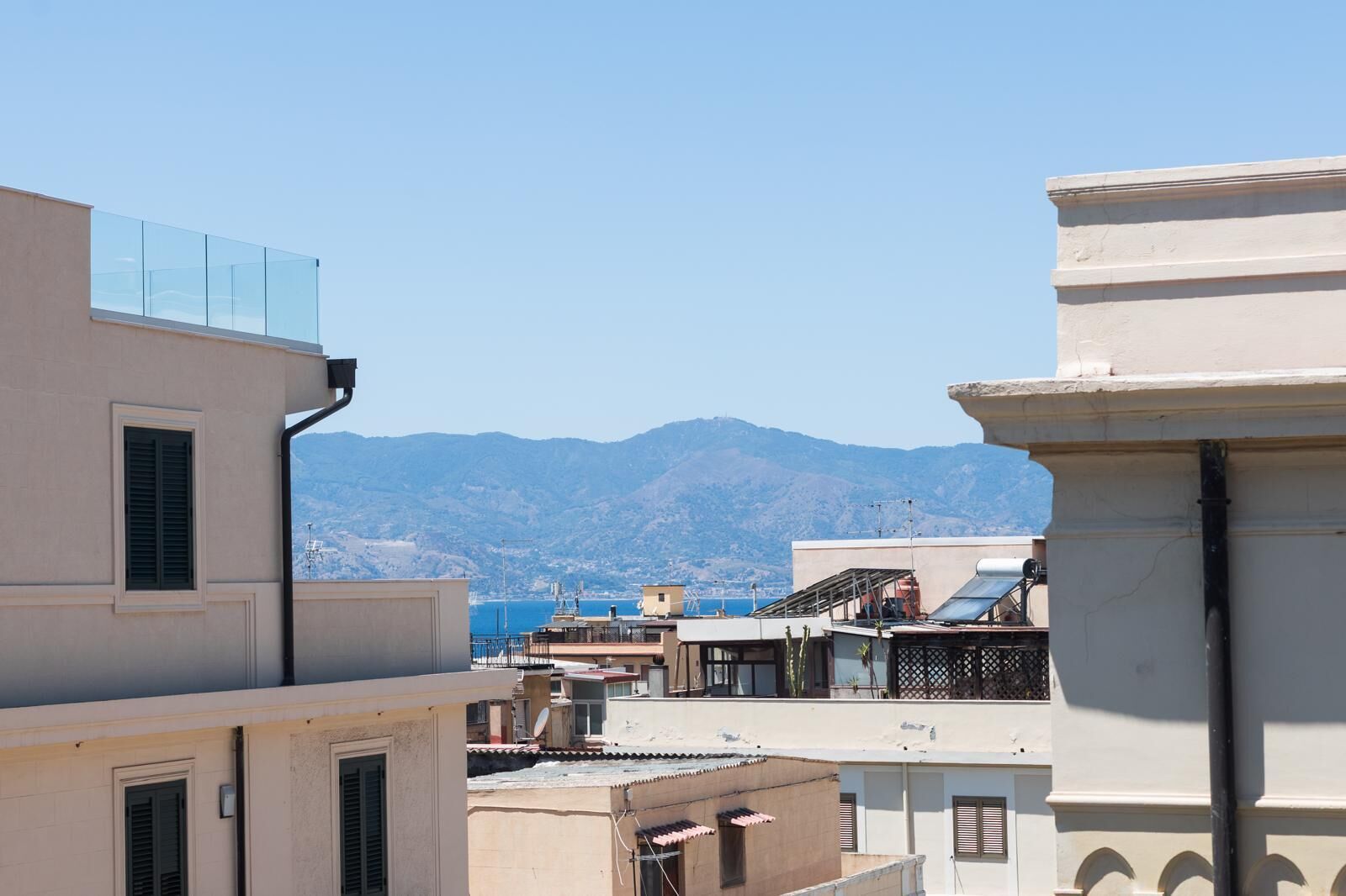 Una vista di una cittadina costiera con edifici che si affacciano sul mare e montagne sullo sfondo.