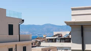 Una vista di una cittadina costiera con edifici che si affacciano sul mare e montagne sullo sfondo.