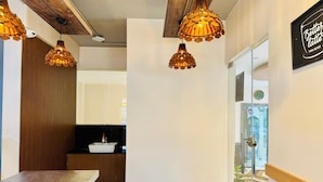 Una cocina moderna con detalles de madera, iluminación colgante y un lavamanos a la vista.
