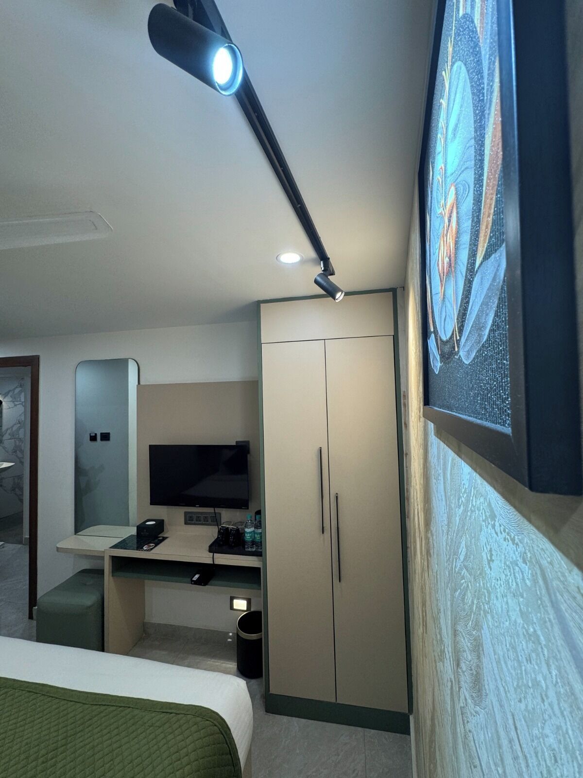 Une chambre d’hôtel comprenant un lit, un bureau avec un téléviseur à écran plat, une armoire et un tableau au mur.
