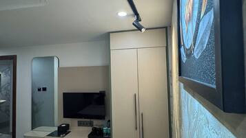 Une chambre d’hôtel comprenant un lit, un bureau avec un téléviseur à écran plat, une armoire et un tableau au mur.