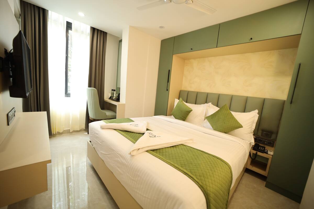 Habitación de hotel con una cama grande, un escritorio, una silla, un televisor y una mesita de noche con teléfono.