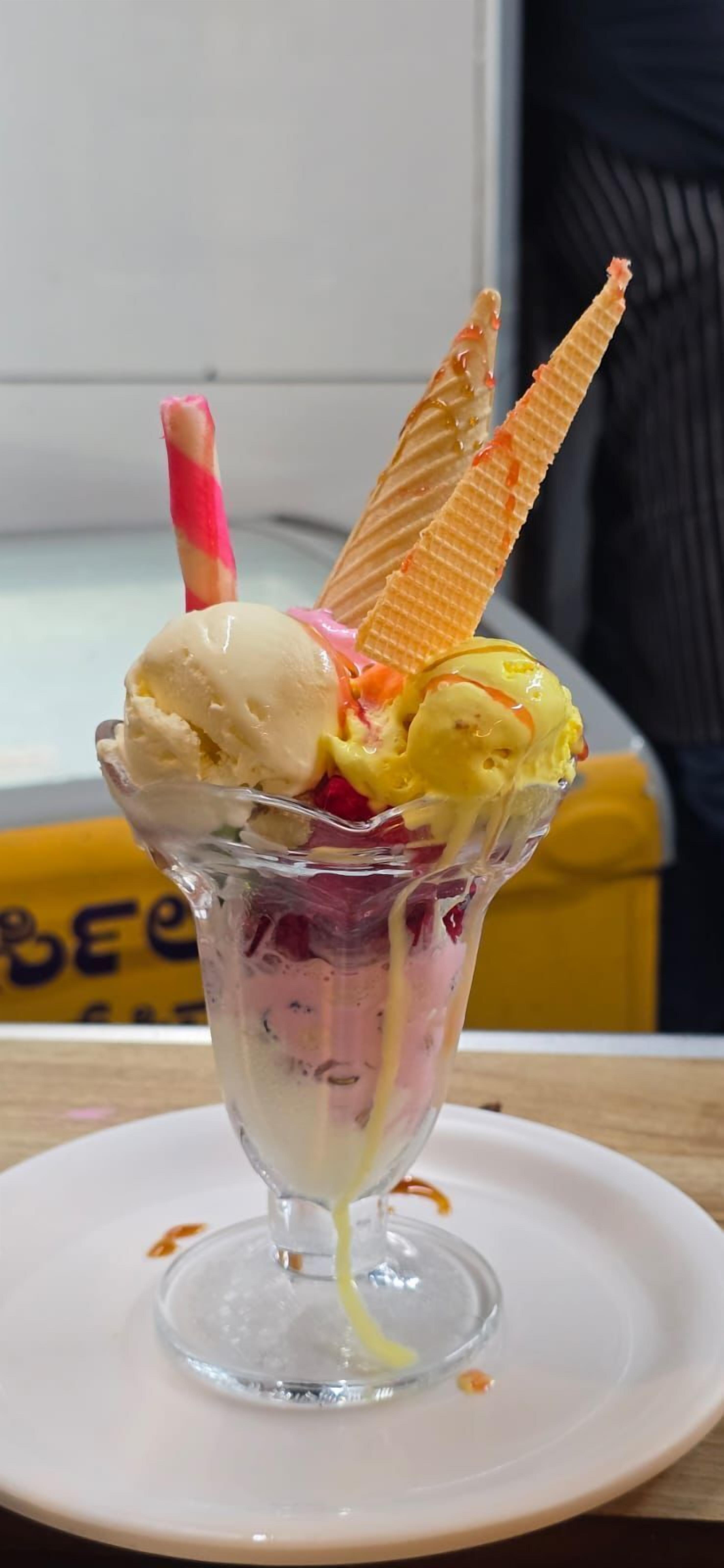 Un postre en vaso con cono de gofre y pajita rosa.