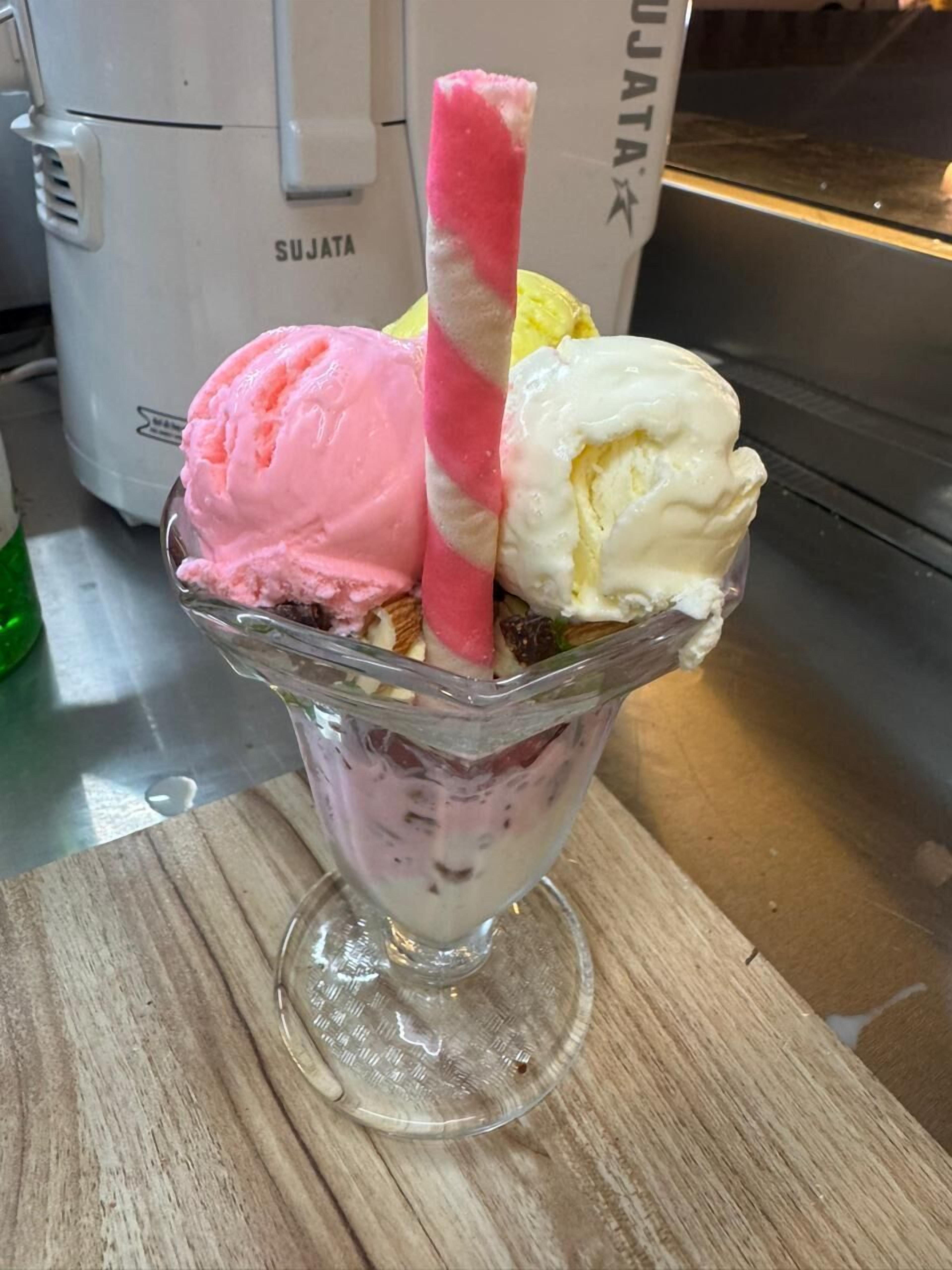A dessert with three scoops of ice cream in a glass bowl.
