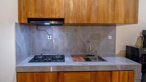 Een keuken met houten kastjes, een gasfornuis, een gootsteen en een marmeren achterwand.
