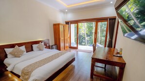 Een slaapkamer met een groot bed, een houten garderobe, een eettafel en uitzicht op groen door het raam.