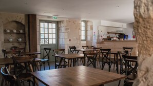 Un restaurante con mesas y sillas de madera, una zona de cocina y una pared de piedra.