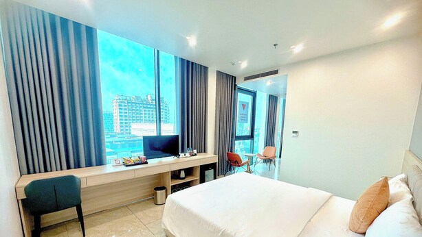 Une chambre d’hôtel avec un lit, un bureau, une chaise, une télévision et une vue sur la ville.