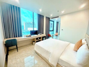 Habitación de hotel con cama, escritorio, silla, televisor y vista a la ciudad.