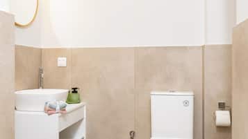 Uma casa de banho moderna com uma sanita, uma pia branca e um porta-toalhas.