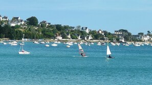 Une ville côtière où l’on voit de nombreux bateaux sur l’eau et des maisons en arrière-plan.