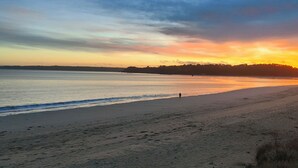 A beach with a person walking along the shore, a calm sea, and a sunset sky. - La maison du Soleil 4* ☀️,completed in 2025,near RN12 with high-speed wifi (Bodilis)