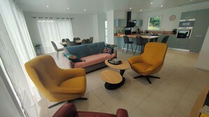 A modern living room with a sofa, two armchairs, a coffee table, and a dining area with chairs and a table. - La maison du Soleil 4* ☀️,completed in 2025,near RN12 with high-speed wifi (Bodilis)