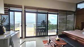 Un balcón con vista al mar, una cama, un escritorio y una silla.