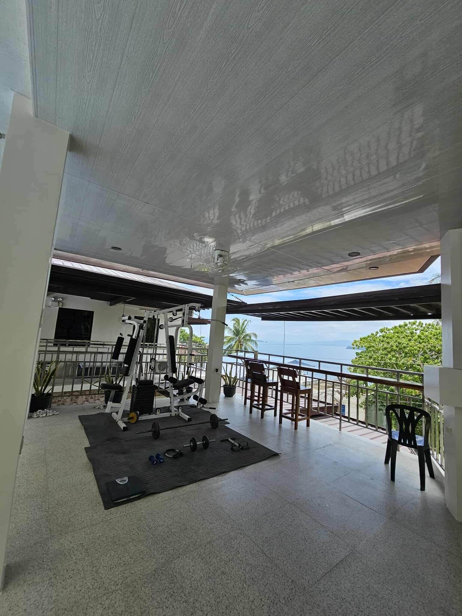 A gym with exercise equipment and a view of the sea.