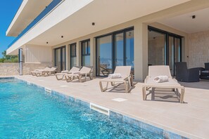 Área da piscina com espreguiçadeiras e um muro de pedra.