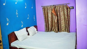 A room with a bed, a curtain, and wall decorations. - New Balagi Guest House (Barakpur)
