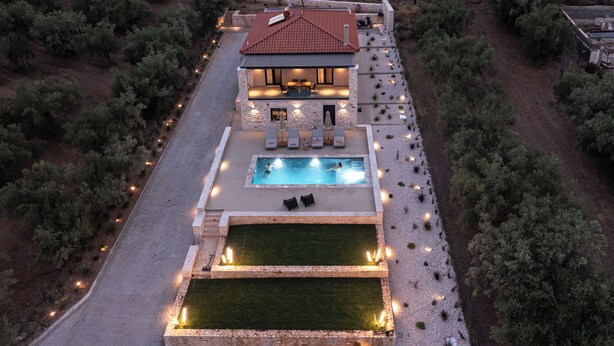 A two-story house with a swimming pool, outdoor seating, and a well-lit patio area.