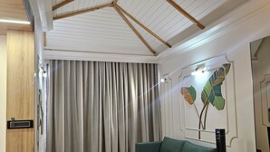 A modern room with a wooden ceiling, a green sofa, a flat-screen TV, and a wooden floor. - M Farm Resort (Rajkot)