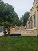 Um pátio com piscina, uma fonte e um edifício com varanda.