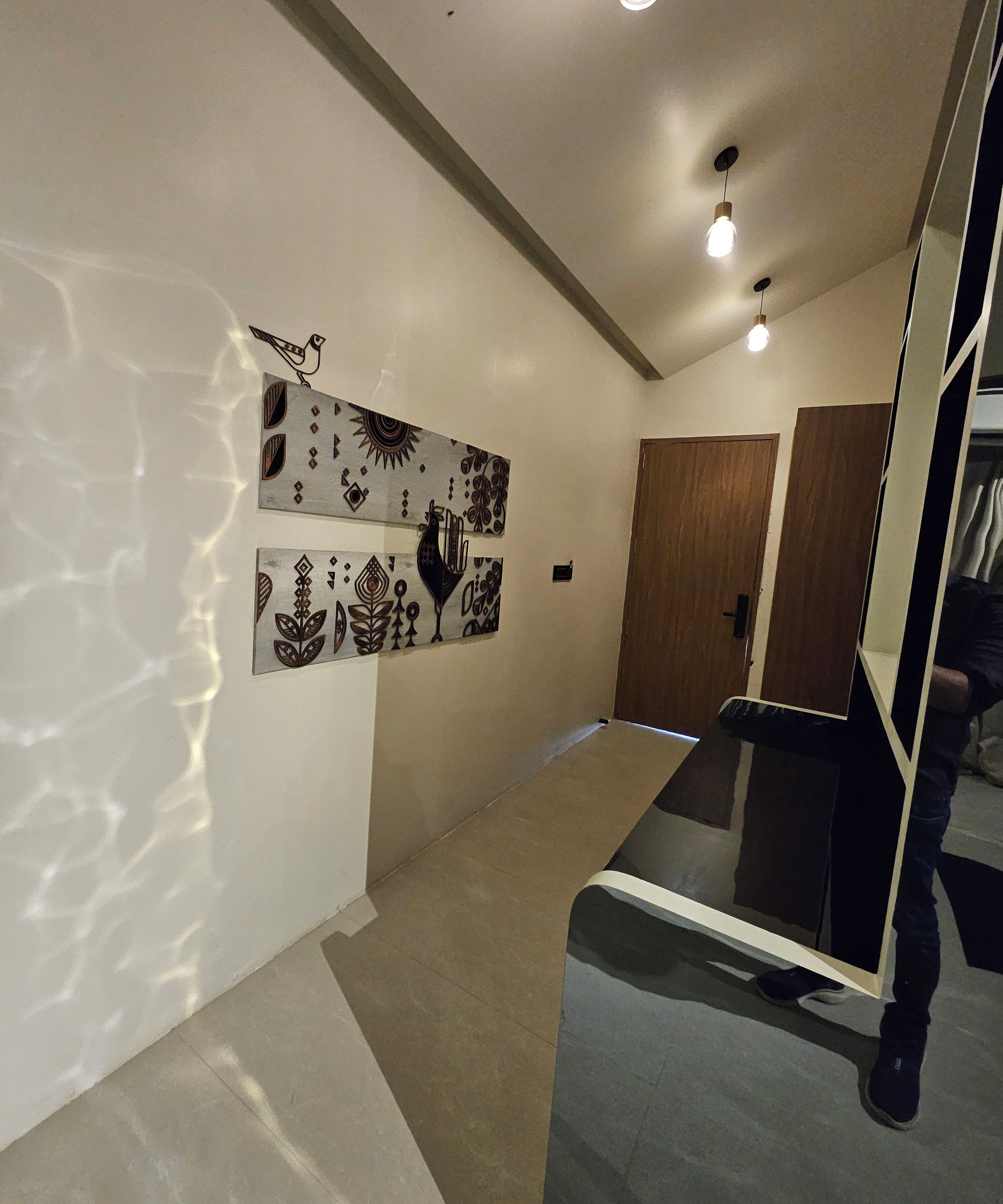 Un pasillo de diseño moderno con un separador de vidrio, puertas de madera y obras de arte en la pared.